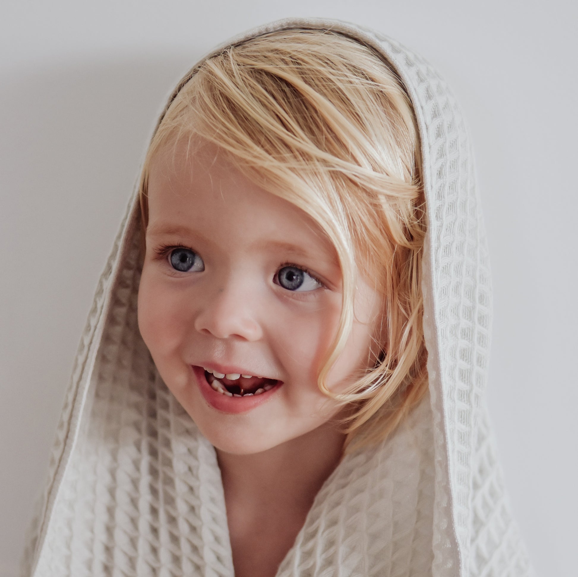 smiling child wearing light grey dove coloured organic cotton waffle towel