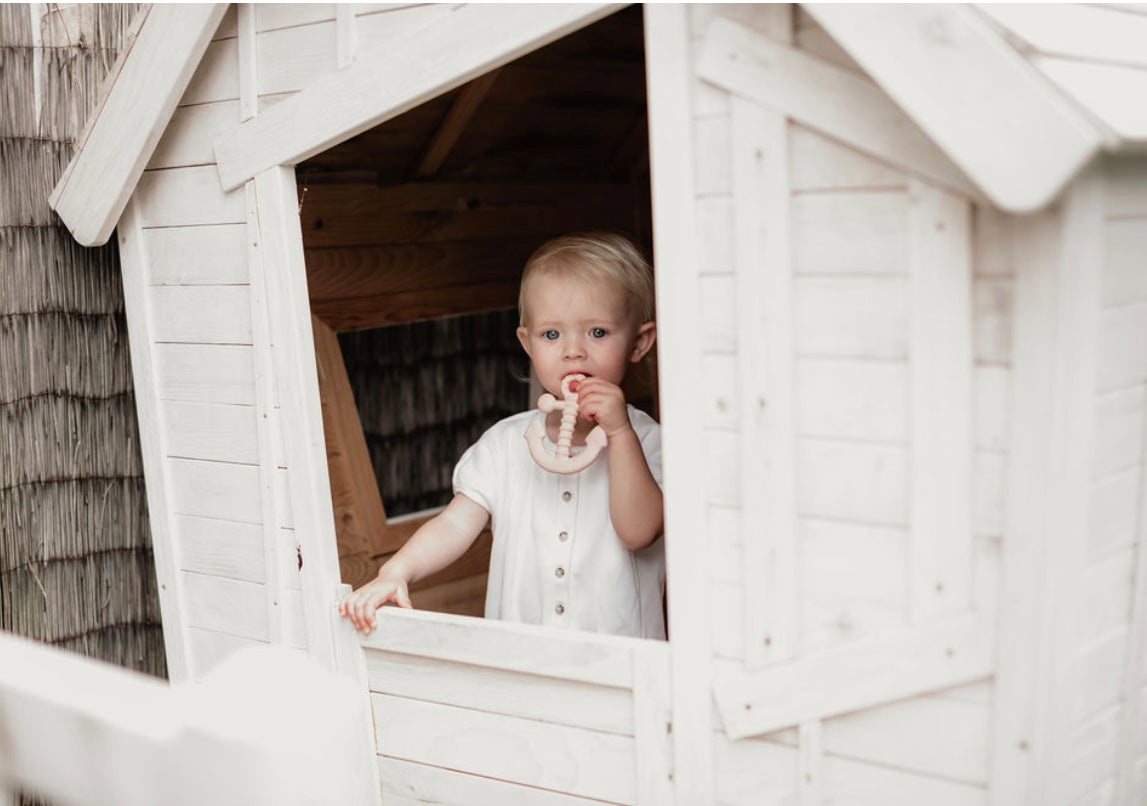 Toddler chewing natural rubber EveEco baby anchor teether in a cubby house