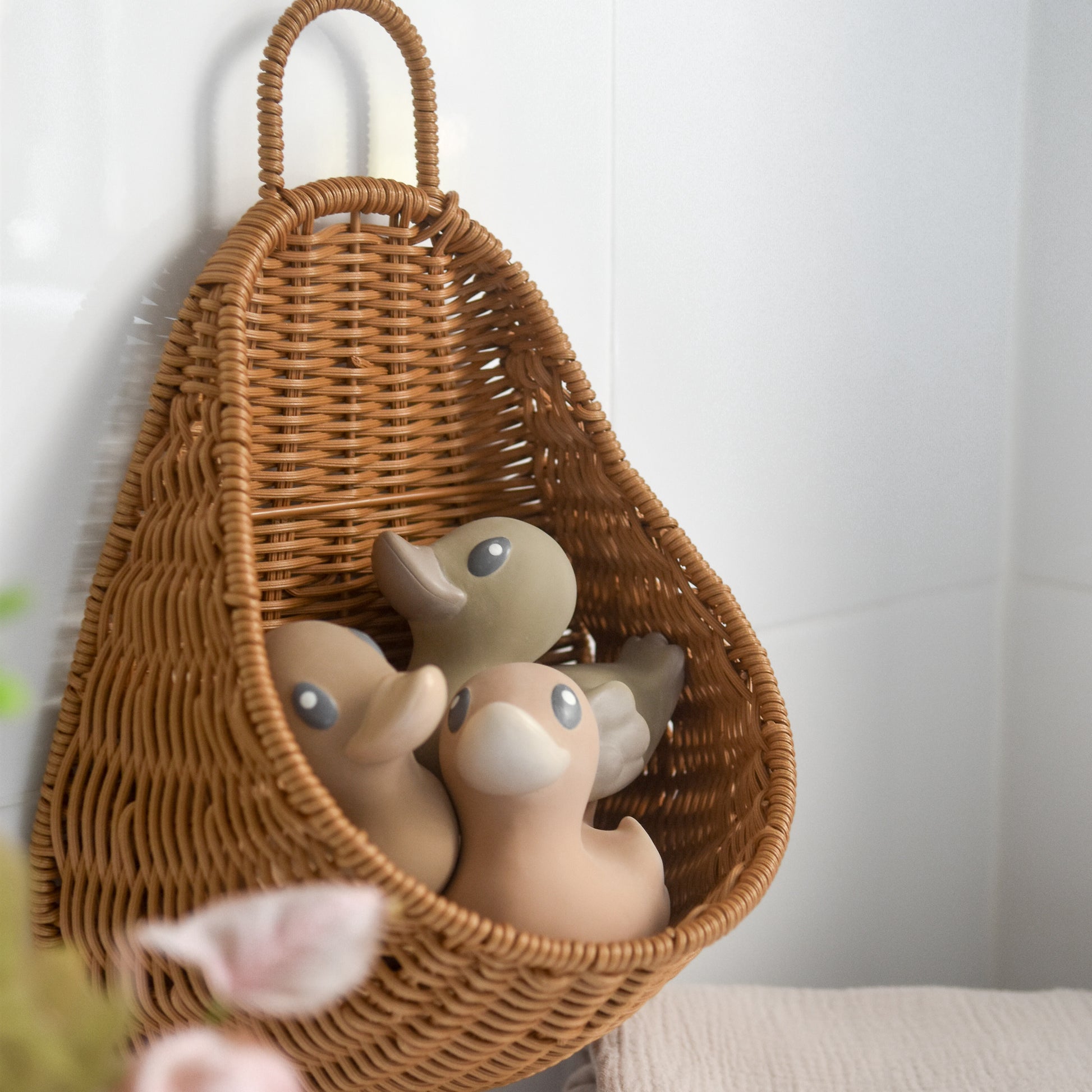 bath storage basket woven from recycled plastic rattan storing three rubber duck bath toy