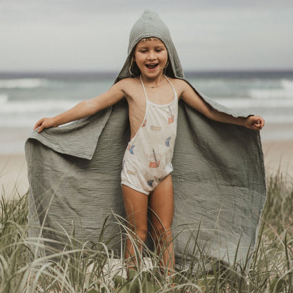 A child smiling while wearing a storm green organic hooded cotton towel