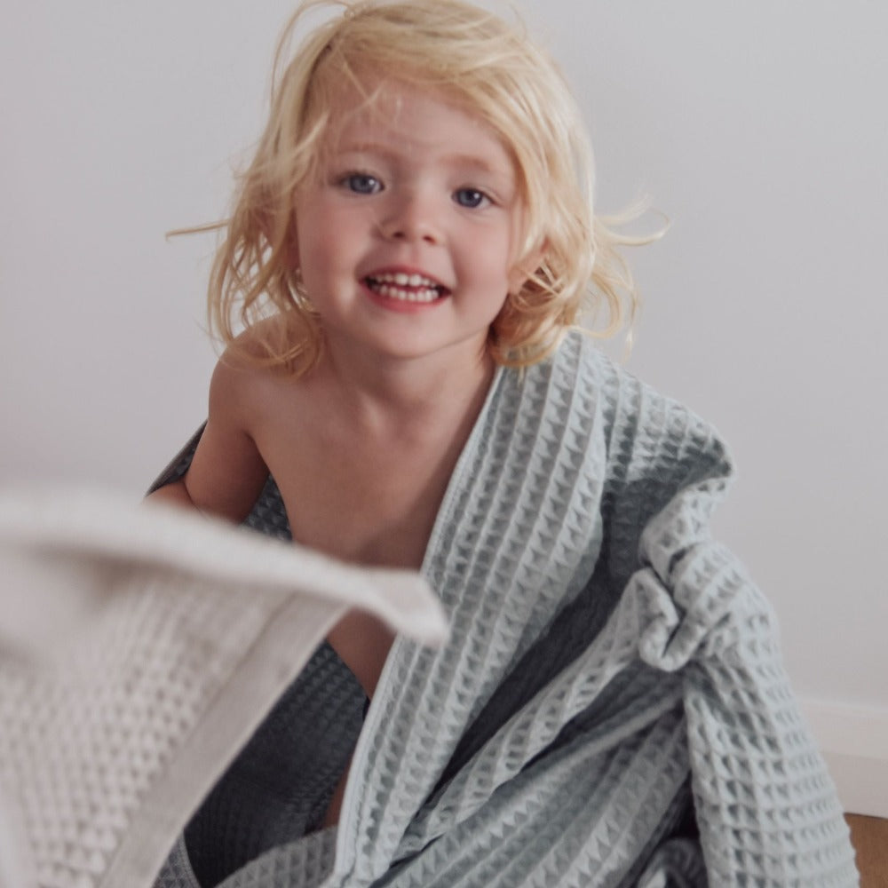 girl smiling and dancing wearing seafoam blue green organic cotton waffle towel