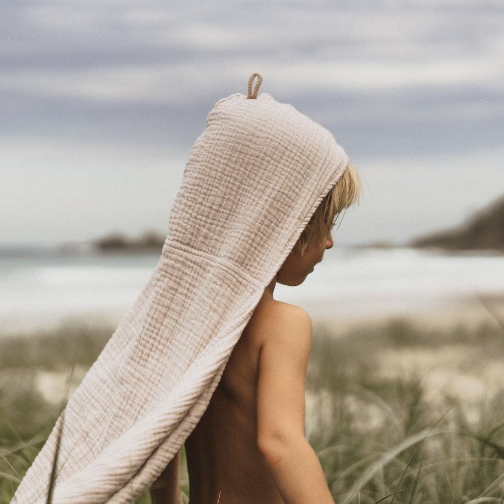 child facing away wearing the neutral tan coloured organic cotton hooded towel on his head
