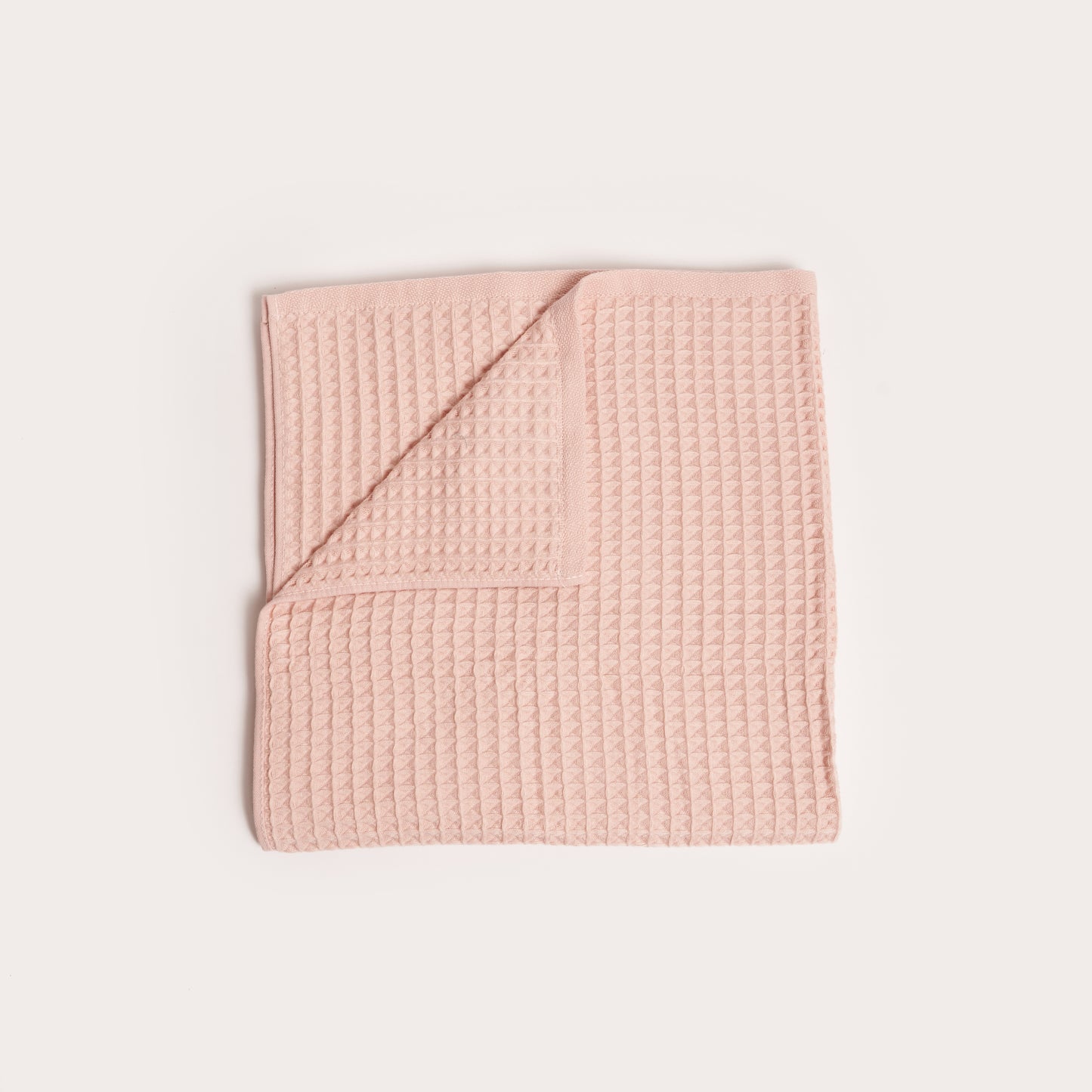 pink taffy coloured folded organic cotton waffle towel with one corner folded down