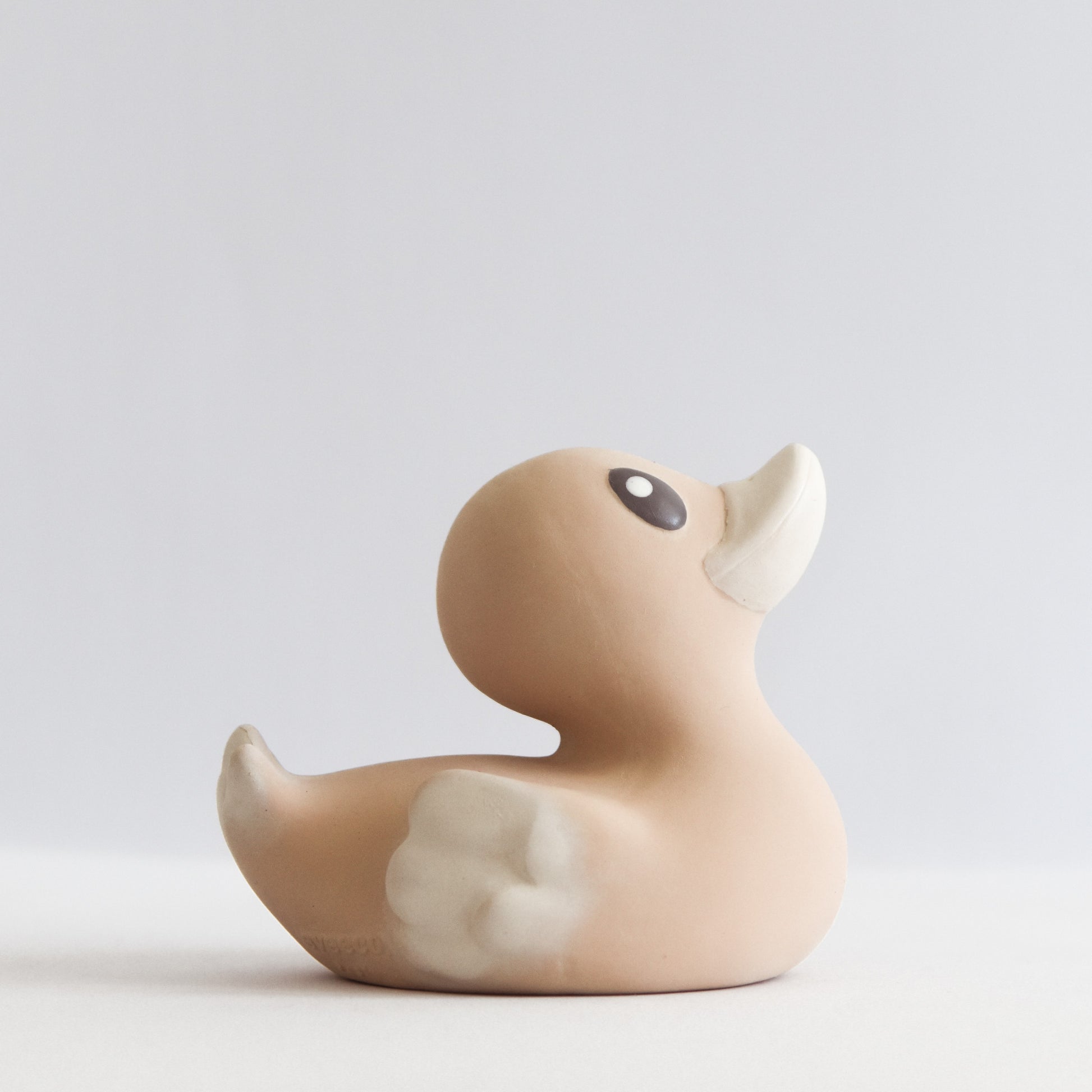 side view of an adorable natural rubber bath toy duck in a light brown peach colour