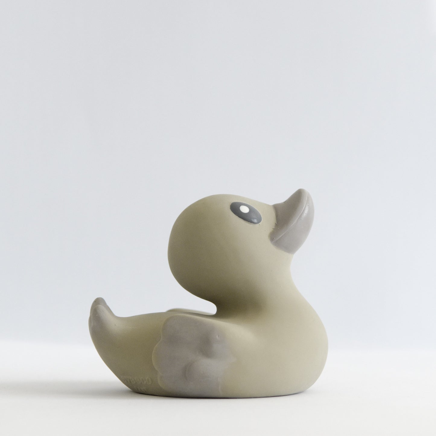 side view of an adorable natural rubber bath toy duck in a neutral brown grey colour